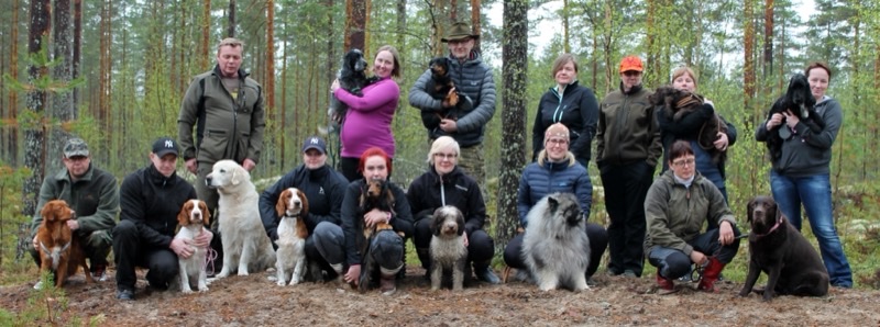 Seuran jäsenet koirineen ryhmäkuvassa metsässä